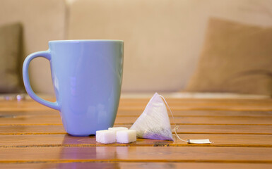 view of cup of tea with tea bag, sugar cube on wooden table