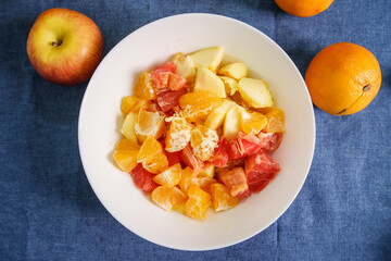 TOp view of various fruit in the white bowl on the table at home - fruit salad healthy eating concept vegan or vegetarian food ready to eat
