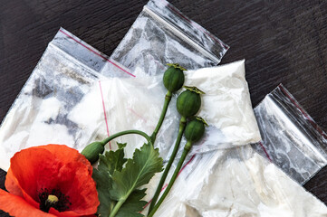 flowers and opium poppy heads next to packages of heroin, soft focus, toning