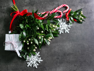 Mistletoe bunches, gift box, decorations and space for text on grey background, above view....
