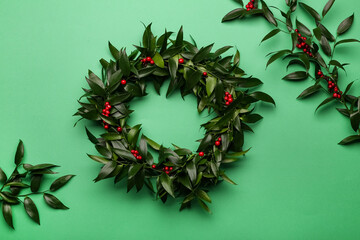 Beautiful handmade mistletoe wreath on green background, flat lay. Traditional Christmas decor