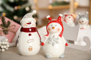 Cute decorative snowmen on table against blurred background