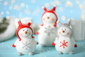 Three decorative snowmen on light blue table
