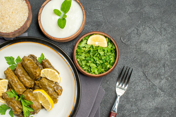 top view bowls with natural yogurt parsley rice dolma on white plate a fork a purple kitchen towel on dark background with copy space