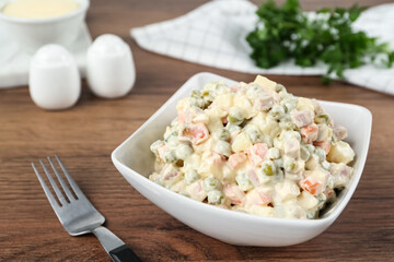 Traditional russian salad Olivier served on wooden table