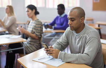 Portrait of focused man using mobile phone during adult education class