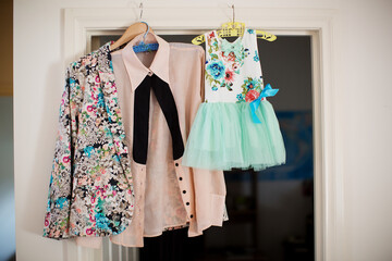 Womans wedding outfit and her daughters dress hung up on a door frame