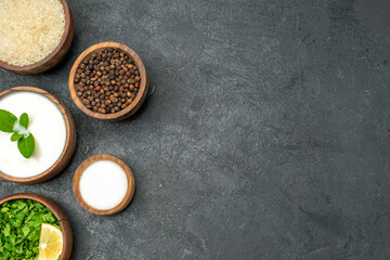 top close view wooden bowls with rice natural yogurt parsley black pepper salt on dark background with copy space