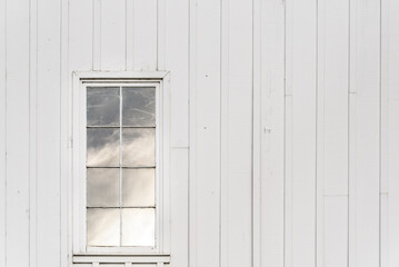 Closeup of exterior of white traditional barn with window reflecting the sky  © knelson20