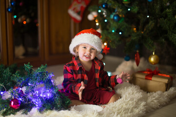 a child in red clothes is sitting waiting for the new year. the concept of celebrating Christmas at midnight. holiday costume