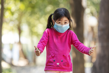 Lovely little girl makeing sign of  joyfully when they wearing medical   face and playing at the...