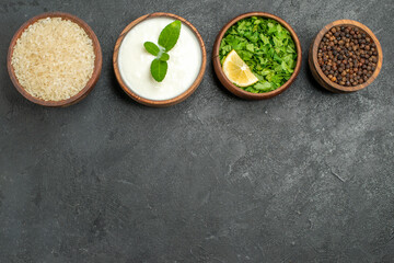 top view horizontal row bowls with rice natural yogurt parsley black pepper on dark background with copy space