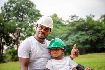 Cheerful african american father and son in hard hat having a picnic in the park, Happiness family concepts