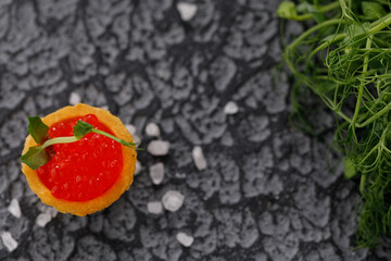 Appetizing tartlet with red caviar and microgreen decor. Holiday concept. Close-up. Copy space. Flat lay.