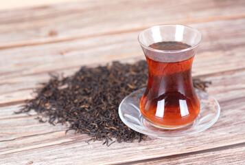 A cup of Turkish black tea and scattered tea leaves