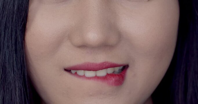Close up half female face smiling and biting lips in shyness