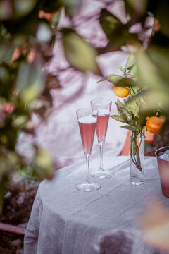 Table near the orange tree in the garden with two glasses of sparkling rose wine