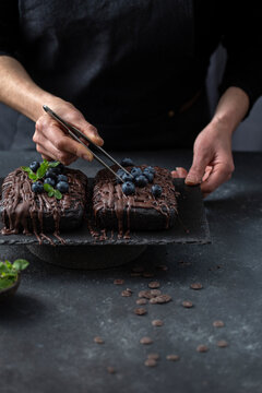 Pastry chef decorates brownie cake with blueberries and mint leaves