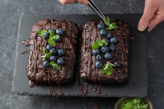 Pastry chef decorates brownie cake with blueberries and mint leaves