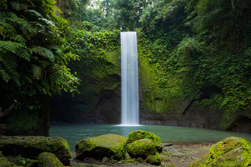 Naklejka na ściany i meble Waterfall landscape. Beautiful hidden waterfall in tropical rainforest. Nature background. Slow shutter speed, motion photography. Tibumana waterfall, Bali, Indonesia