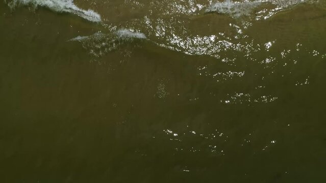 Top down view of sea shore and flowing waves. Aerial backwards shoot
