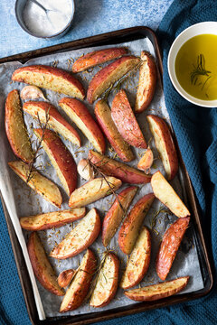 Seasoned potato wedges on a baking tray.