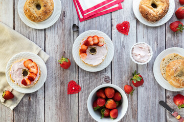 Top down view of breakfast table of bagels with cream cheese and strawberries.