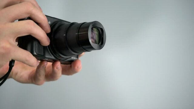 Using, zooming, and taking picture with  small superzoom point-and-shoot camera from Canon with white background studio shot