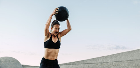 Sportswoman doing intense workout with medicine ball