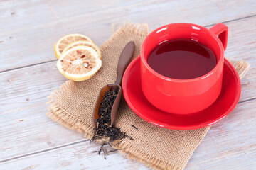 A cup of tea with tea leaves and lemon slices