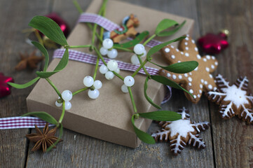 box tied with ribbon, mistletoe sprigs, red glass Christmas toys, gingerbread cookie on a dark wooden background. New Year, Christmas.