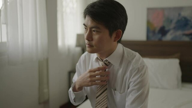 Unemployed stressed young Asian business sitting on bed at home because His Business company shutdown due to outbreak of Coronavirus 2019.Debt,Company recession and layoff concept.Edit Dramatic tone