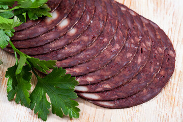 Slices of traditional Spanish blood sausage Botifarra with fresh greens on wooden surface