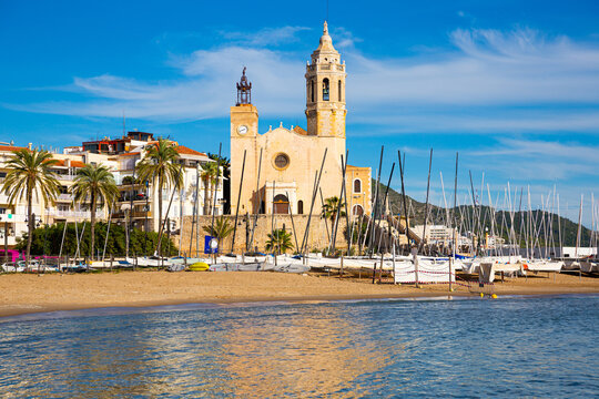 View from sea of Sitges beach and Church of St. Bartholomew and Santa Tecla on sunny fall day, Catalonia, Spain