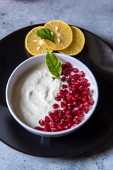 Red pomegranate seeds on curd along with slices of lemon with use of selective focus.