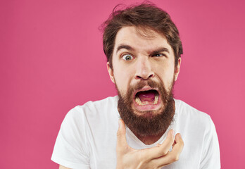 Man holds his hands near his face on a pink background stress irritability anger