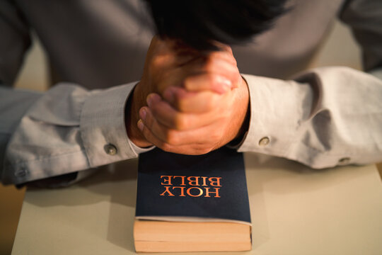 holy bible on table in chruch and man praying for god blessing