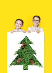 Happy little kids peeking from Christmas banner blank on yellow background. Kids holding banner blank with Christmas tree. Sale, holidays, christmas, new year, x-mas concept.