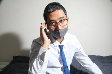 室内で電話をしているマスクをしたビジネスマンの横顔