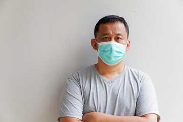 Middle-aged man standing with his arms crossed and wearing a mask. To prevent contagious disease coronavirus with copy space