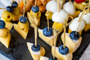 assorted cheeses, blueberries and olives on skewers. appetizers.