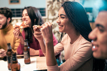 House party concept. Friendship concept with people having. A group of multiracial guys spend good time together in friendship eating pizza and drinking beers. focus on the afro-American woman smiling