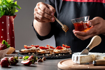 chef sprinkle the honey sweet sandwiches with strawberries, cheese, camembert, brie, nuts and honey...