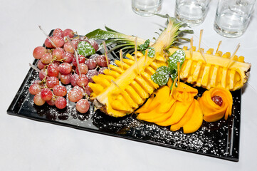 Grapes, pineapple and persimmon are beautifully served on a porcelain platter.
