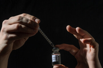 Ampoule with covid-19 vaccine and syringe for injection on black background	
