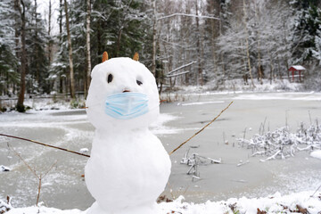 snowman in a protective mask in the snow