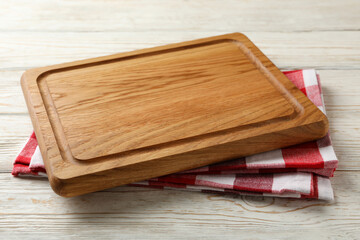 Kitchen towel and wooden board on white wooden background