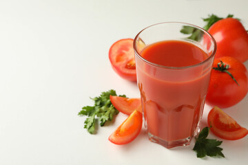 Glass of tomato juice, tomatoes and parsley on white background