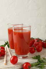 Board with tomato juice and tomatoes on white textured background