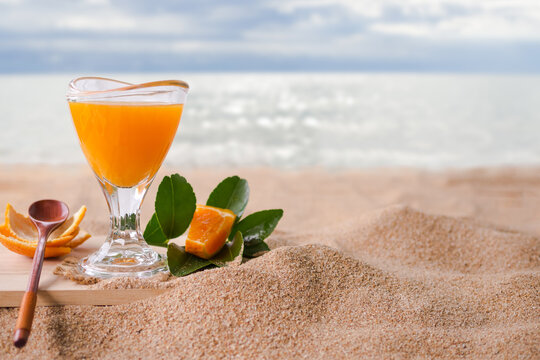 orange juice in glasss on sand beach with blur image of sea. Tropical fruit juice for drink summer holiday, hi vitamin C. food and drink concept.